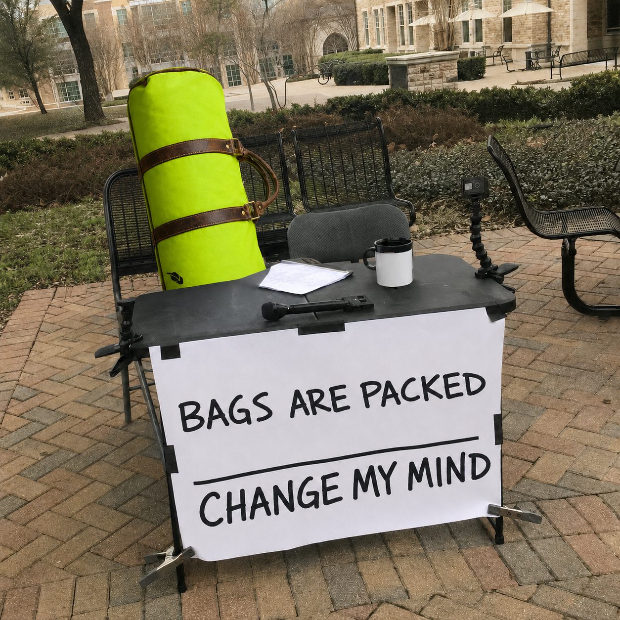 A packed duffle bag behind a table with a Bags are packed, change my mind sign